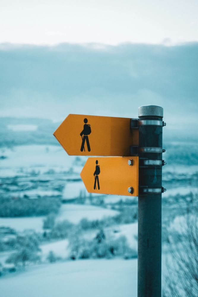 Yellow hiking signposts on a snowy hill